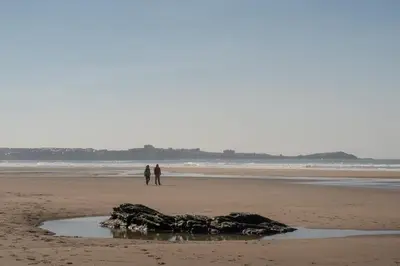 two people standing on a beach with a rock in the sand at Ground Floor Couples Retreat in Newquay