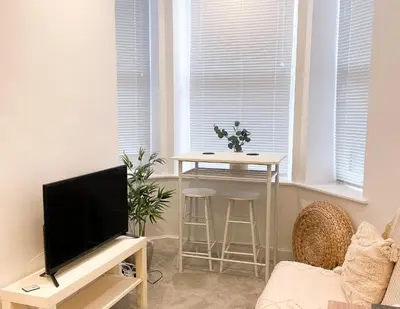a living room with a television and a table with stools at Ground Floor Couples Retreat in Newquay