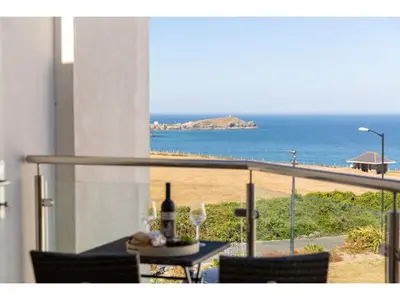 a table with a bottle of wine and a view of the beach at Modern Apartment Sea Views Private Parking in Newquay