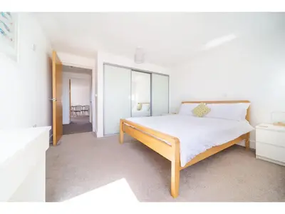 a white bedroom with a bed and a mirror at Modern Apartment Sea Views Private Parking in Newquay