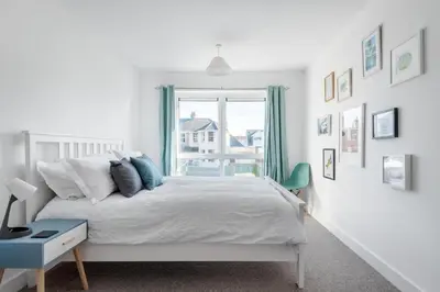 a white bedroom with a bed and a window at Spacious Flat Sea Views & Private Parking Fistral in Newquay