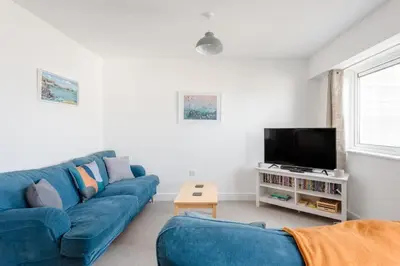 a living room with a blue couch and a tv at Spacious Flat Sea Views & Private Parking Fistral in Newquay