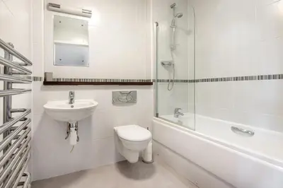 a white bathroom with a toilet and a sink at Spacious Flat Sea Views & Private Parking Fistral in Newquay