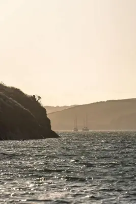two boats floating on the water near a cliff at Spacious Flat Sea Views & Private Parking Fistral in Newquay