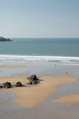 a beach with rocks in the sand and the ocean at Cosy Apartment Parking Central Newquay in Newquay