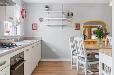 a kitchen with white cabinets and a wooden table at Modern Townhouse in Penryn with Private Parking in Penryn