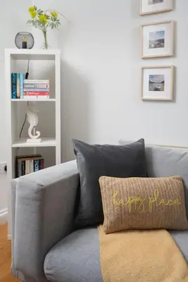 a gray couch in a living room with a book shelf at Family Home in Newquay Parking 3 mins to Beach in Newquay
