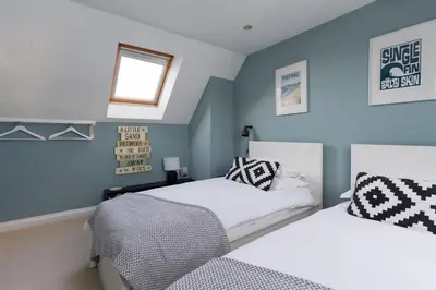 two beds in a bedroom with blue walls and a window at Family Home in Newquay Parking 3 mins to Beach in Newquay