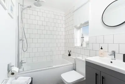 a white bathroom with a tub and a toilet and a sink at Family Home in Newquay Parking 3 mins to Beach in Newquay
