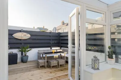 a patio with a table and chairs on a balcony at Family Home in Newquay Parking 3 mins to Beach in Newquay