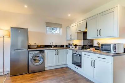 a kitchen with white cabinets and a washer and dryer at 2 Bed in Tywardreath oc-a30310 in Tywardreath