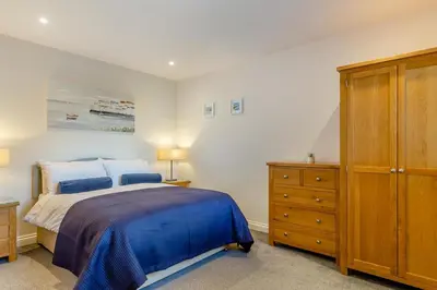 a bedroom with a bed and a wooden dresser at 2 Bed in Tywardreath oc-a30310 in Tywardreath