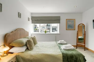 a bedroom with a bed with a green bedspread and a window at Ranalegh Court in Saint Columb Minor