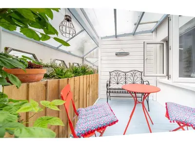 a patio with a red table and chairs and a bench at Spacious Home Private Parking Central Newquay in Newquay