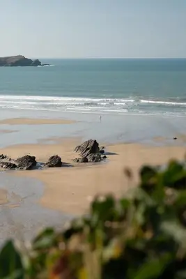 a beach with rocks in the sand and the ocean at Spacious Home Private Parking Central Newquay in Newquay