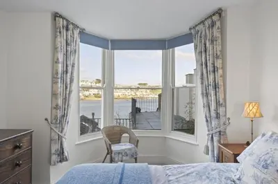 a bedroom with a bed and a large window at Apartment Sea Views & Terrace on Waters Edge in Polruan in Polruan