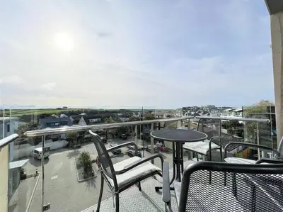 a balcony with chairs and a table on a balcony at Modern Apartment nr Fistral Beach Private Parking in Newquay