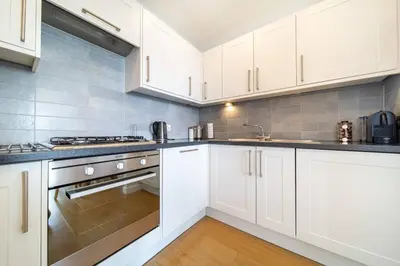a kitchen with white cabinets and stainless steel appliances at Modern Apartment nr Fistral Beach Private Parking in Newquay