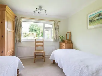 a bedroom with a bed and a chair and a window at Curlew in Wadebridge