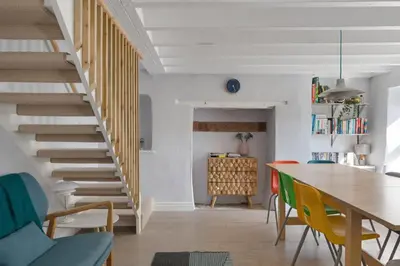 a living room with a staircase and a table and chairs at Cornish Miners Cottage St Agnes in St. Agnes