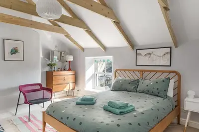 a bedroom with a bed and a chair in it at Cornish Miners Cottage St Agnes in St. Agnes