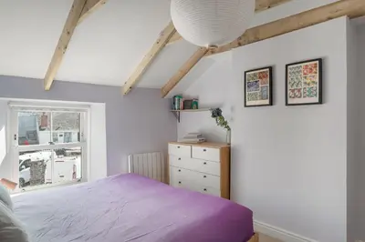 a bedroom with a purple bed and a window at Cornish Miners Cottage St Agnes in St. Agnes