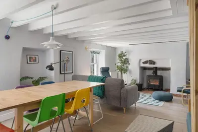 a living room with a table and chairs and a fireplace at Cornish Miners Cottage St Agnes in St. Agnes