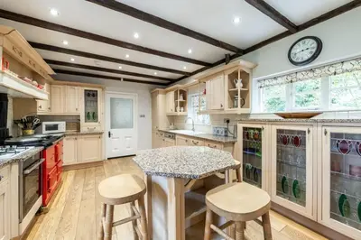 a kitchen with wooden cabinets and a table and stools at Large Grade II Listed House & Garden nr Beaches in Saint Columb Major