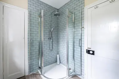 a bathroom with a shower with blue tiles at Large Grade II Listed House & Garden nr Beaches in Saint Columb Major