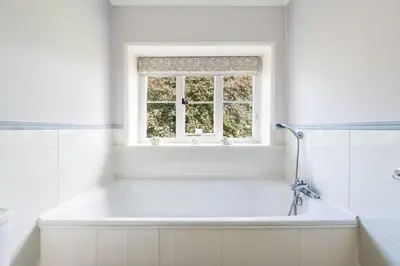 a white bathroom with a tub and a window at Large Grade II Listed House & Garden nr Beaches in Saint Columb Major
