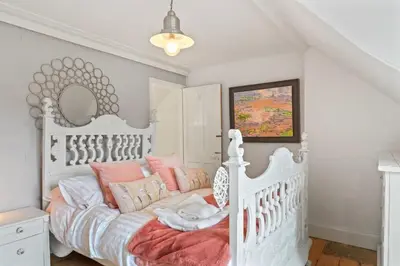a bedroom with a white bed with pink pillows at Cosy Home on the Waterfront Private Parking in Looe