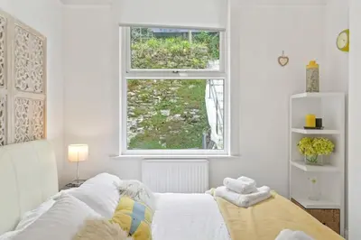 a white bedroom with a bed and a window at Cosy Home on the Waterfront Private Parking in Looe