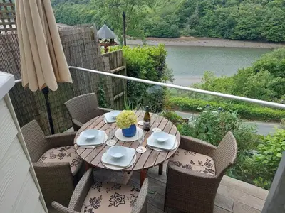 a wooden table and chairs on a balcony at Cosy Home on the Waterfront Private Parking in Looe