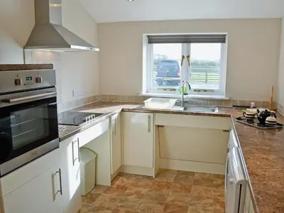 a kitchen with white cabinets and a sink and a window at Swallows in Mount Hawke