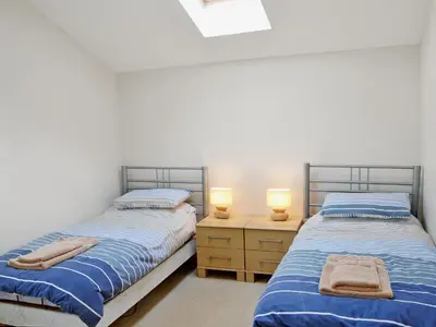 two twin beds in a room with two lamps at Swallows in Mount Hawke