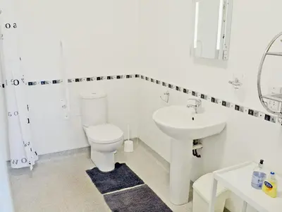 a white bathroom with a toilet and a sink at Swallows in Mount Hawke