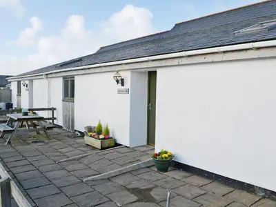 a white building with a patio with a table at Swallows in Mount Hawke