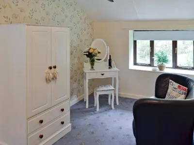a room with a dresser and a table with a chair at Rosecraddoc Manor - Hayloft in Saint Cleer