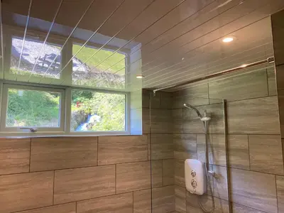a bathroom with a shower and a window at Rosecraddoc Manor - Coachman's in Saint Cleer