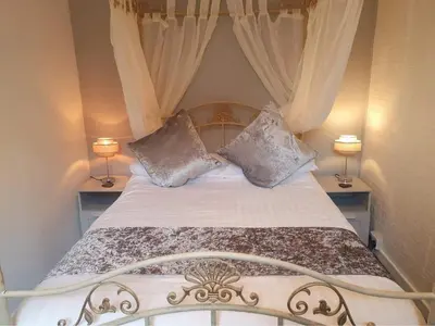 a bedroom with a bed with curtains and two lamps at Rosecraddoc Manor - Coachman's in Saint Cleer