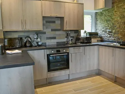 a kitchen with wooden cabinets and a stove top oven at Rosecraddoc Manor - Stable in Saint Cleer