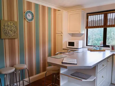 a kitchen with a counter and stools in it at Rosecraddoc Manor - Lakeview in Saint Cleer