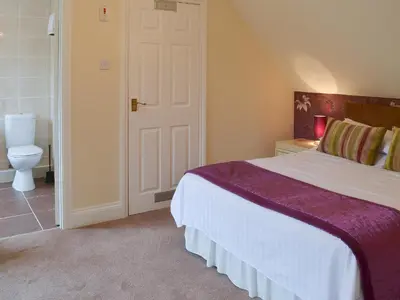 a bedroom with a large bed and a toilet at Rosecraddoc Manor - Lakeview in Saint Cleer
