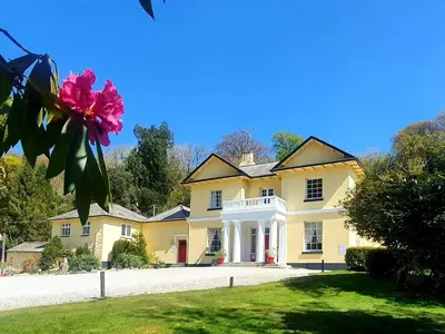 a large yellow house with a flower in the yard at Rosecraddoc Manor - Natalie Jane in Saint Cleer