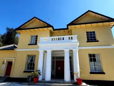 a yellow building with white pillars in front of it at Rosecraddoc Manor - Riverview in Saint Cleer