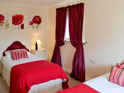 a bedroom with two beds and a window with red curtains at Rosecraddoc Manor - Riverview in Saint Cleer