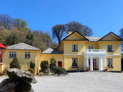 a large yellow house with a large driveway at Rosecraddoc Manor - Riverbank in Saint Cleer