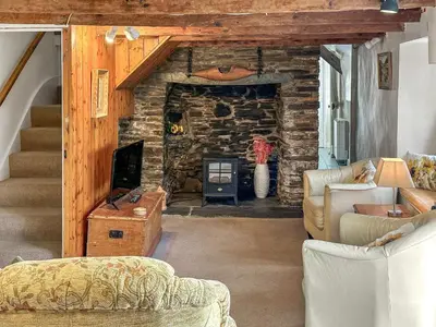 a living room with couches and a stone fireplace at Pillar Box Cottage in Tintagel