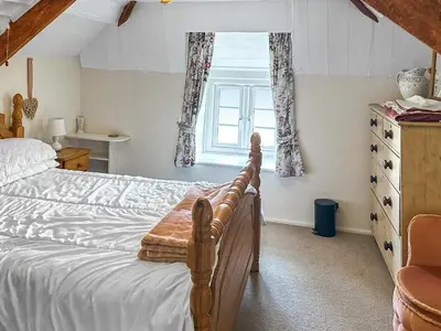 a bedroom with a bed and a window at Pillar Box Cottage in Tintagel