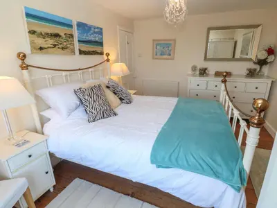 a bedroom with a white bed and a mirror at April Cottage in Falmouth